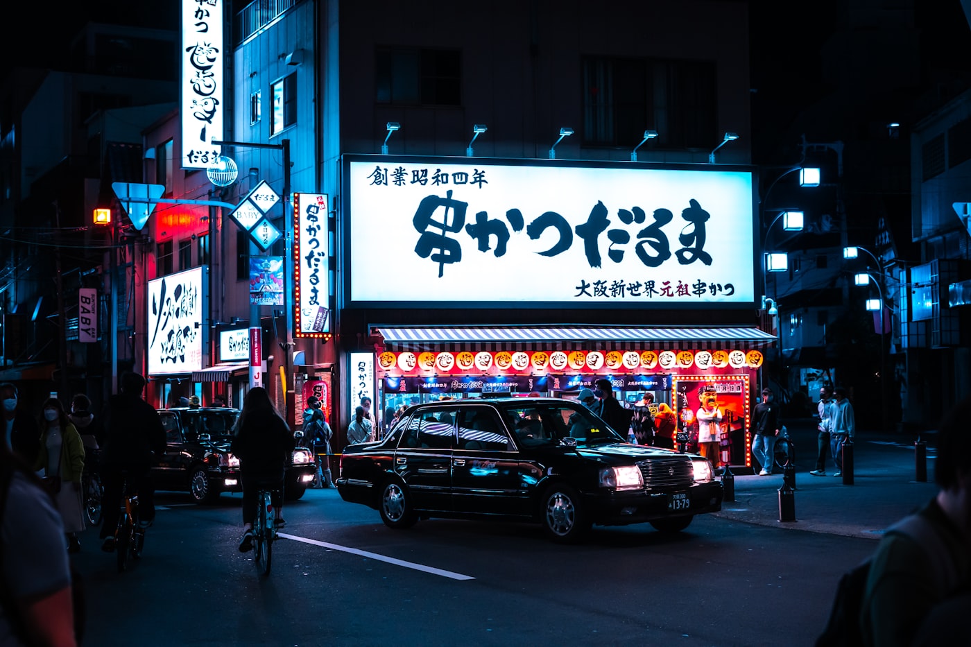 Illuminated restaurant signs beside the Dōtonbori canal at night