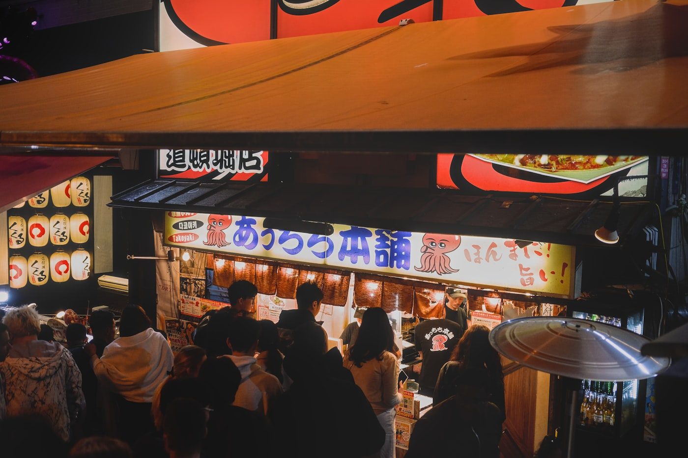 Crowded, brightly lit food stalls in Osaka at night